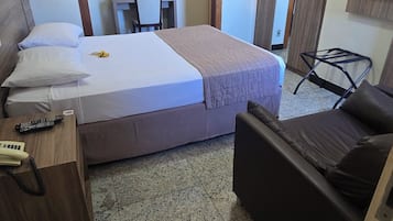 Hotellihuone, jossa on sänky, työpöytä, tuoli ja televisio.