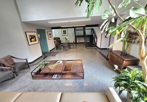 Een ruime lobby met een centrale salontafel, zithoek en een trap.
