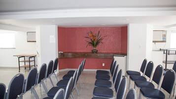 A conference room with rows of chairs, a reception desk, and a decorative plant.