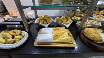 Un bufé con diversos alimentos, incluyendo pan, pasteles y una selección de productos horneados.