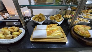 En buffet med forskellige spiser, heriblandt brød, kager og et udvalg af bagværk.