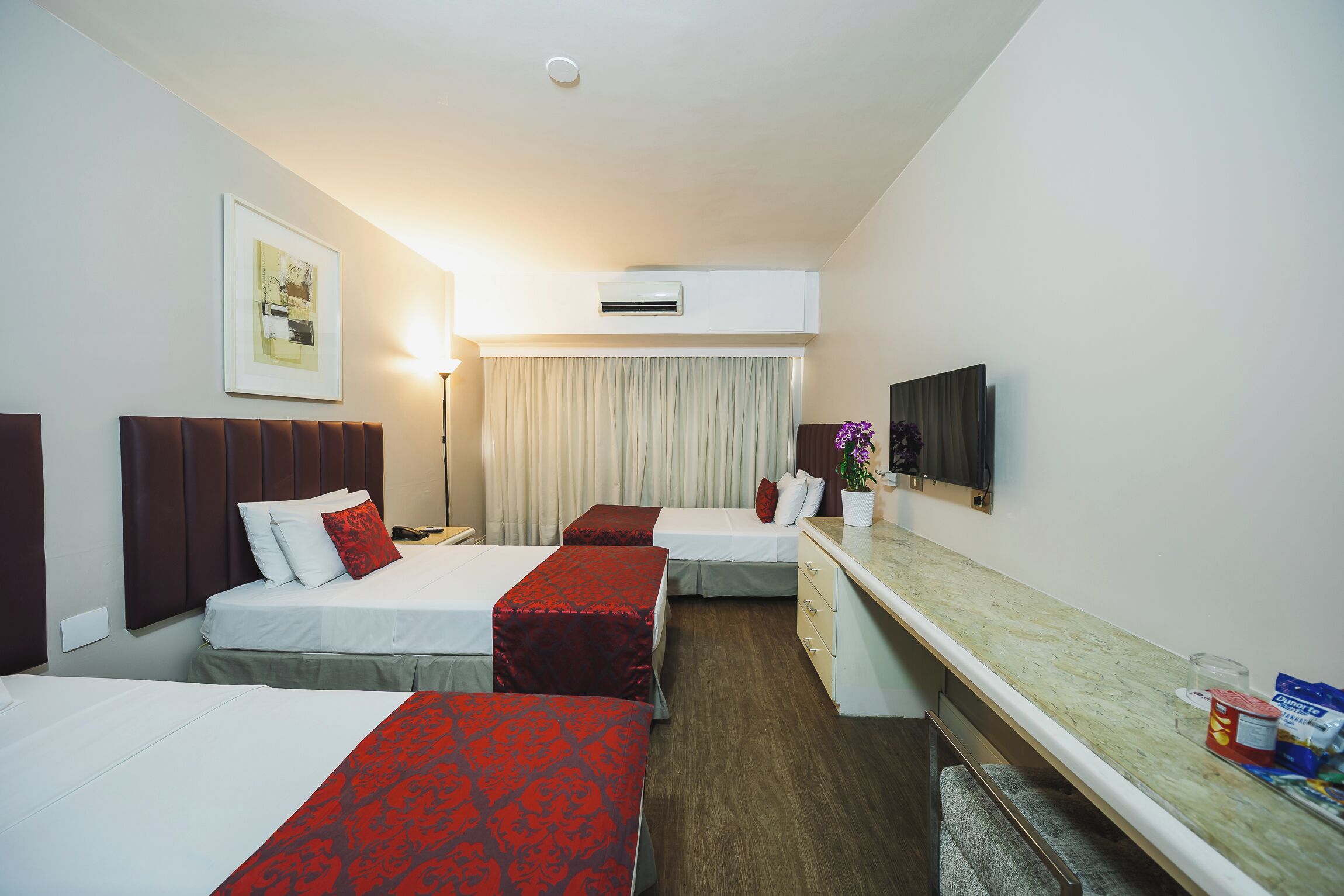 Een hotelkamer met twee bedden, een bureau, een flatscreen-tv en een airconditioner.