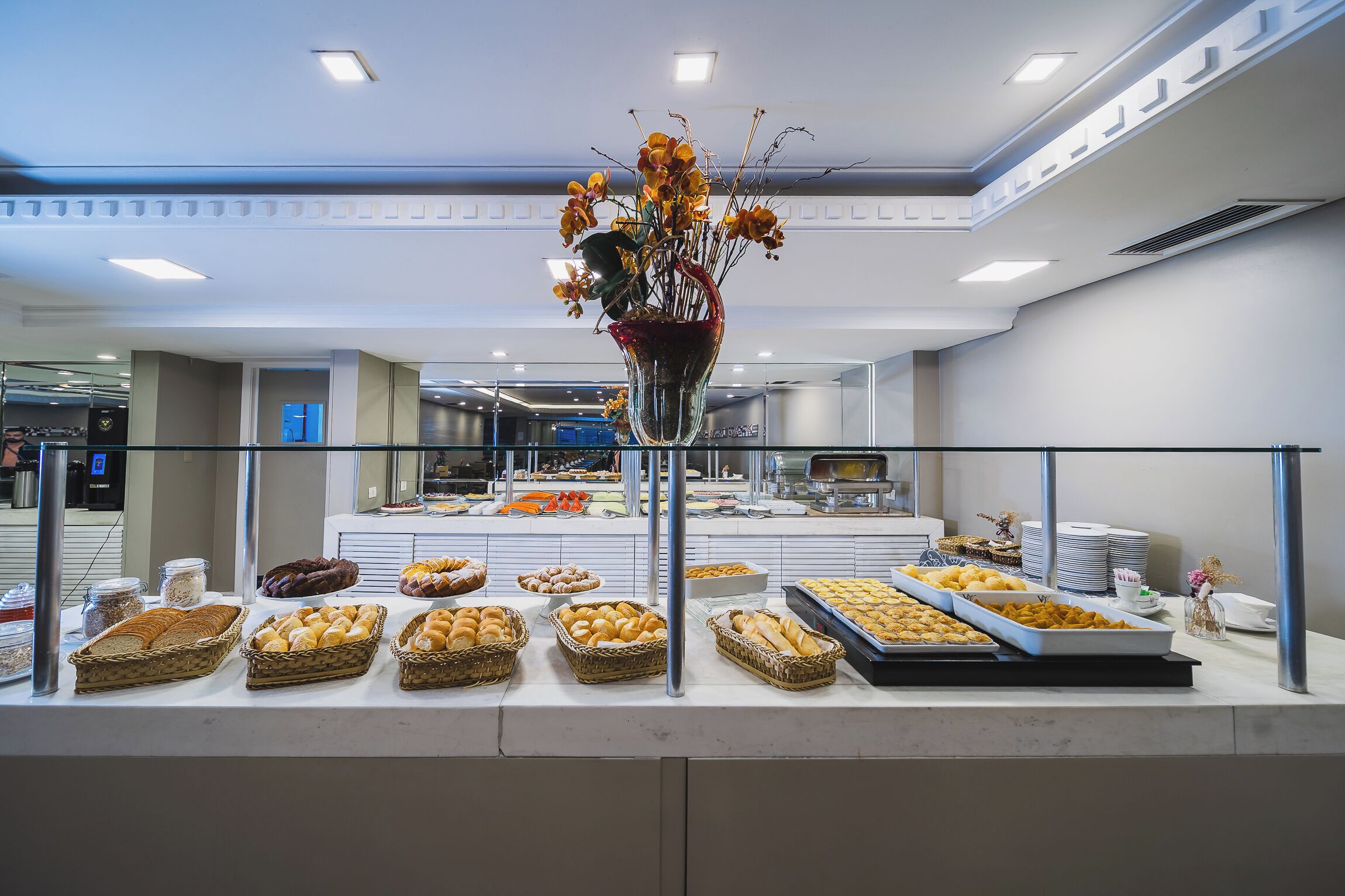 A buffet area with various baked goods and a decorative vase of flowers.