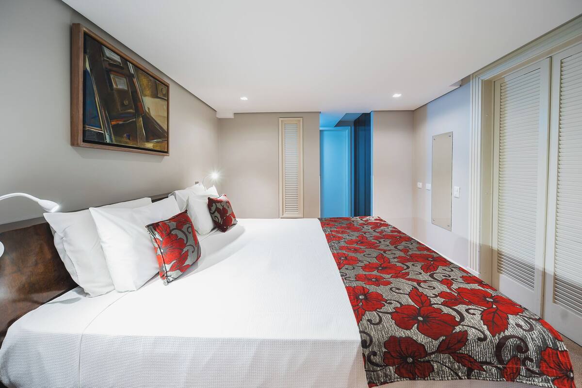 Een slaapkamer met een bed, een schilderij, een deur en een raam.