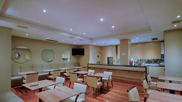 Um restaurante com várias mesas e cabines, área de bar e uma televisão na parede.