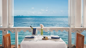 A table set for two with a view of the sea and distant buildings.