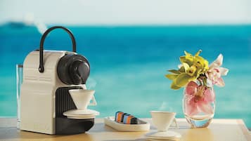 A Nespresso coffee machine on a wooden table with a vase of flowers and a cup of coffee.
