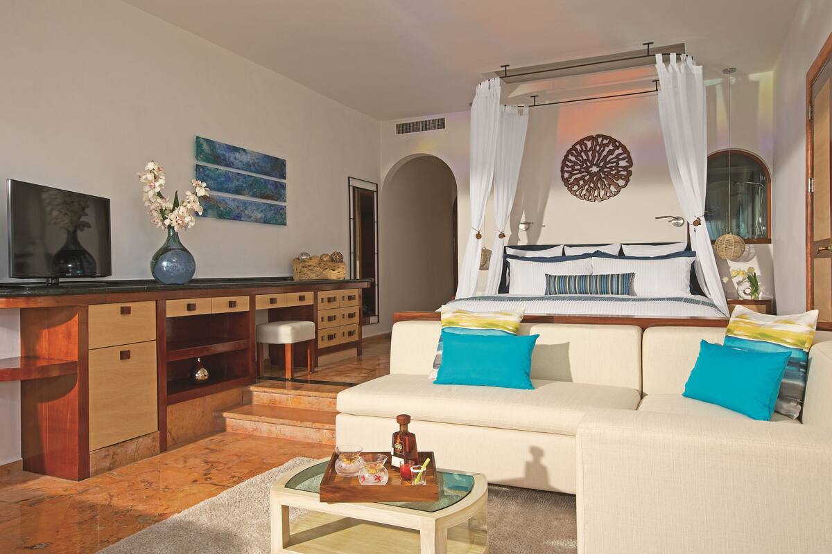 A bedroom with a bed, a sofa, a desk, and a TV.