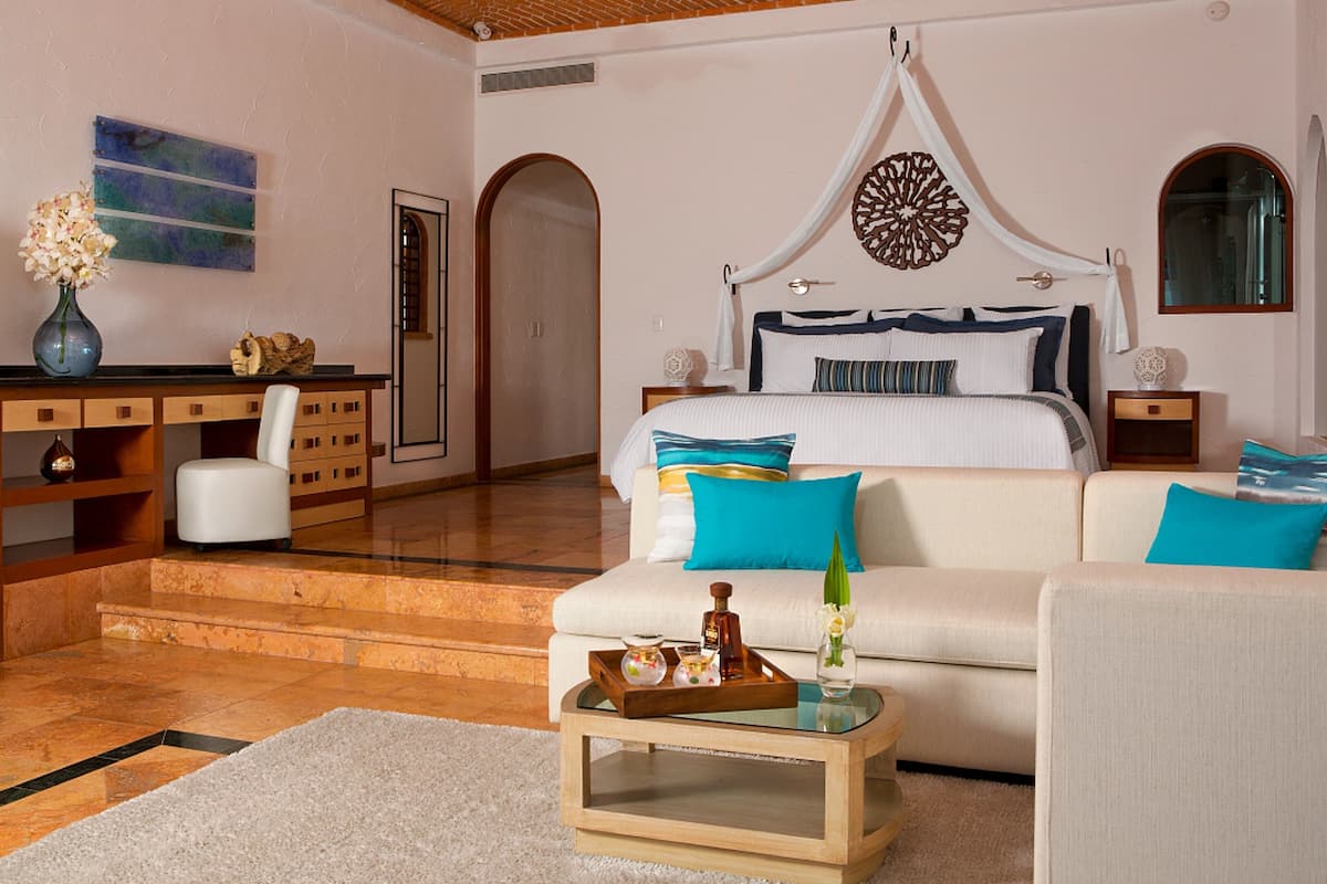 A hotel room with a bed, a desk, a television, and a sofa.