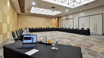 A conference room with a long table, chairs, a laptop, a projector, and a patterned carpet.