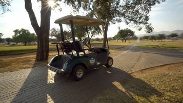 A golf cart parked on a paved path in a park.