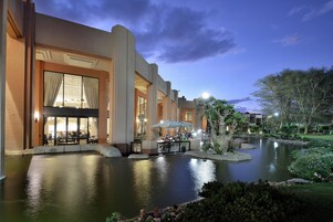 Un hotel con una amplia piscina al aire libre, zona de comedor y entrada bien iluminada.
