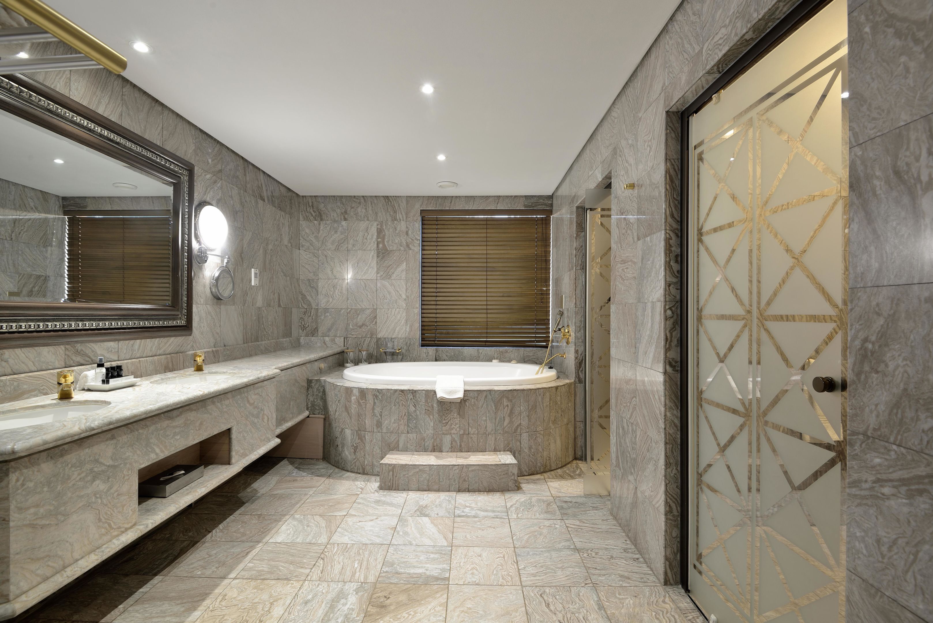 A modern bathroom with a large mirror, two sinks, a bathtub, and a walk-in shower.