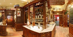 A traditional interior with wooden cabinetry, a counter with glass display, and various signs indicating services like a tobacconist and a pharmacy. - Hotel Waldzeit Berlin - Grünau (Berlin)