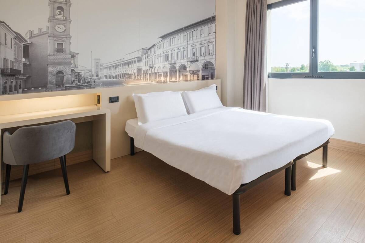 A hotel room with a bed, a desk, and a chair.