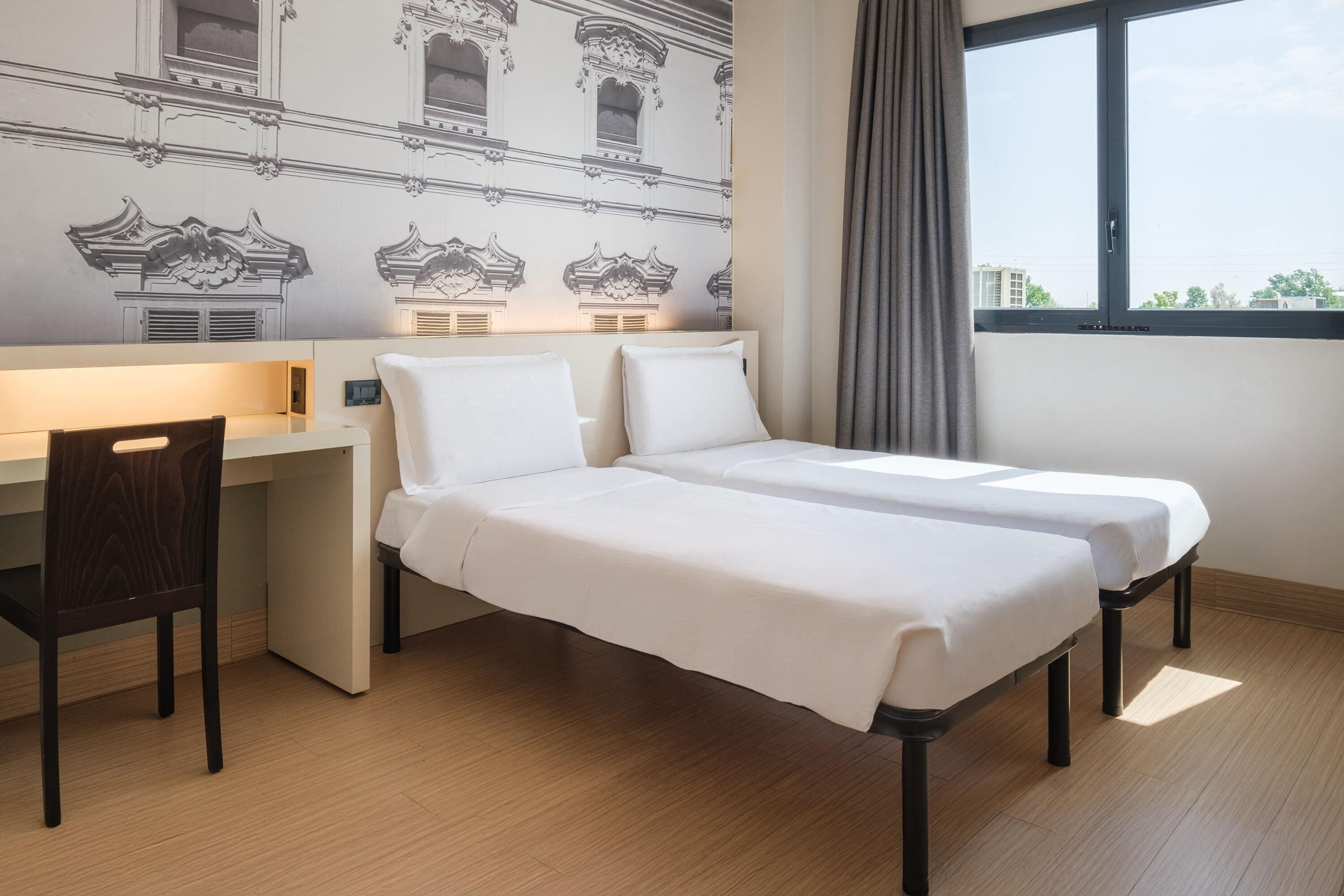 A hotel room with a bed, a desk, and a chair.