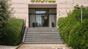 A hotel entrance with a stone facade, a glass door, and steps leading up to the entrance. - B&B Hotel Faenza (Faenza)