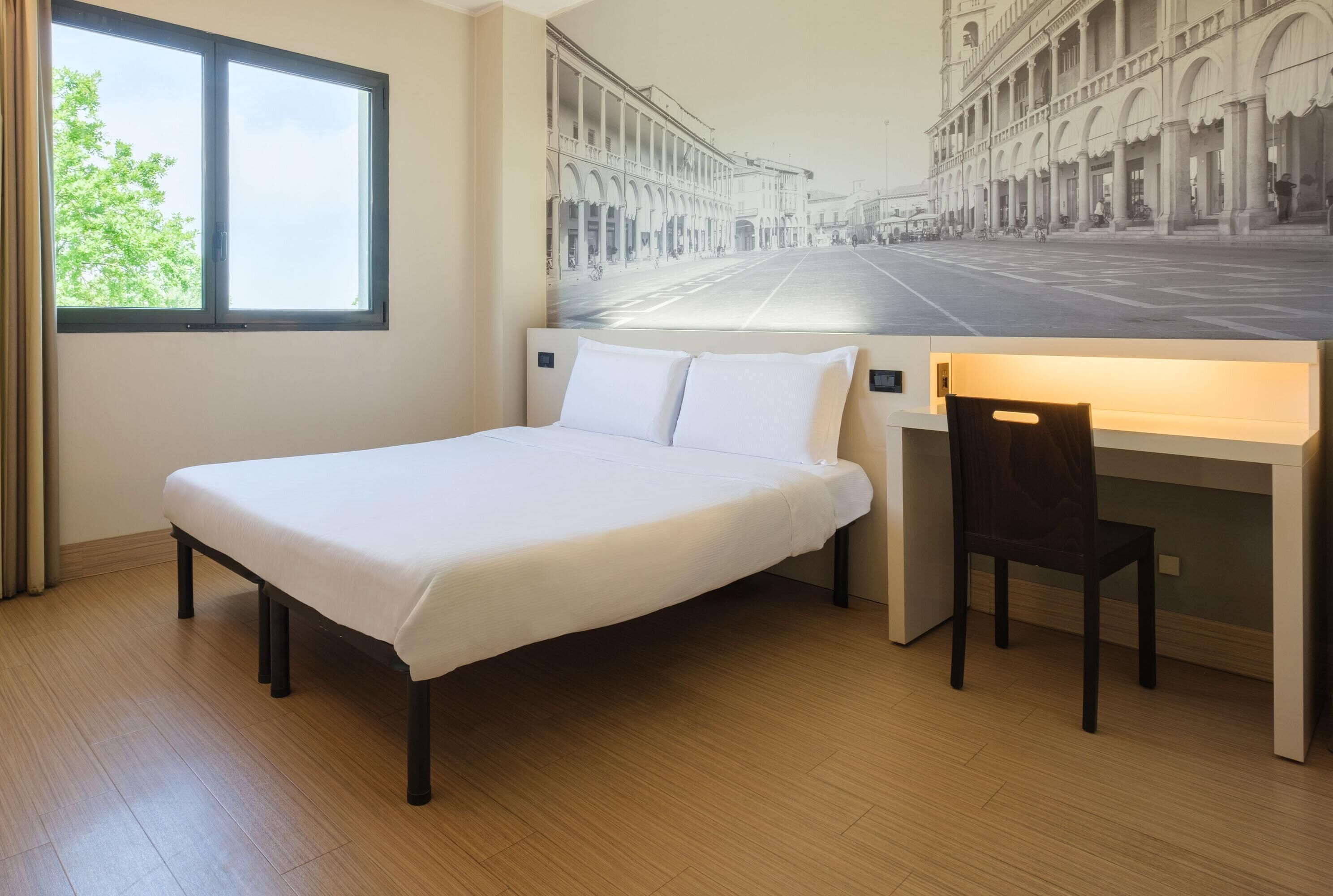 A bedroom with a bed, a desk, and a chair.