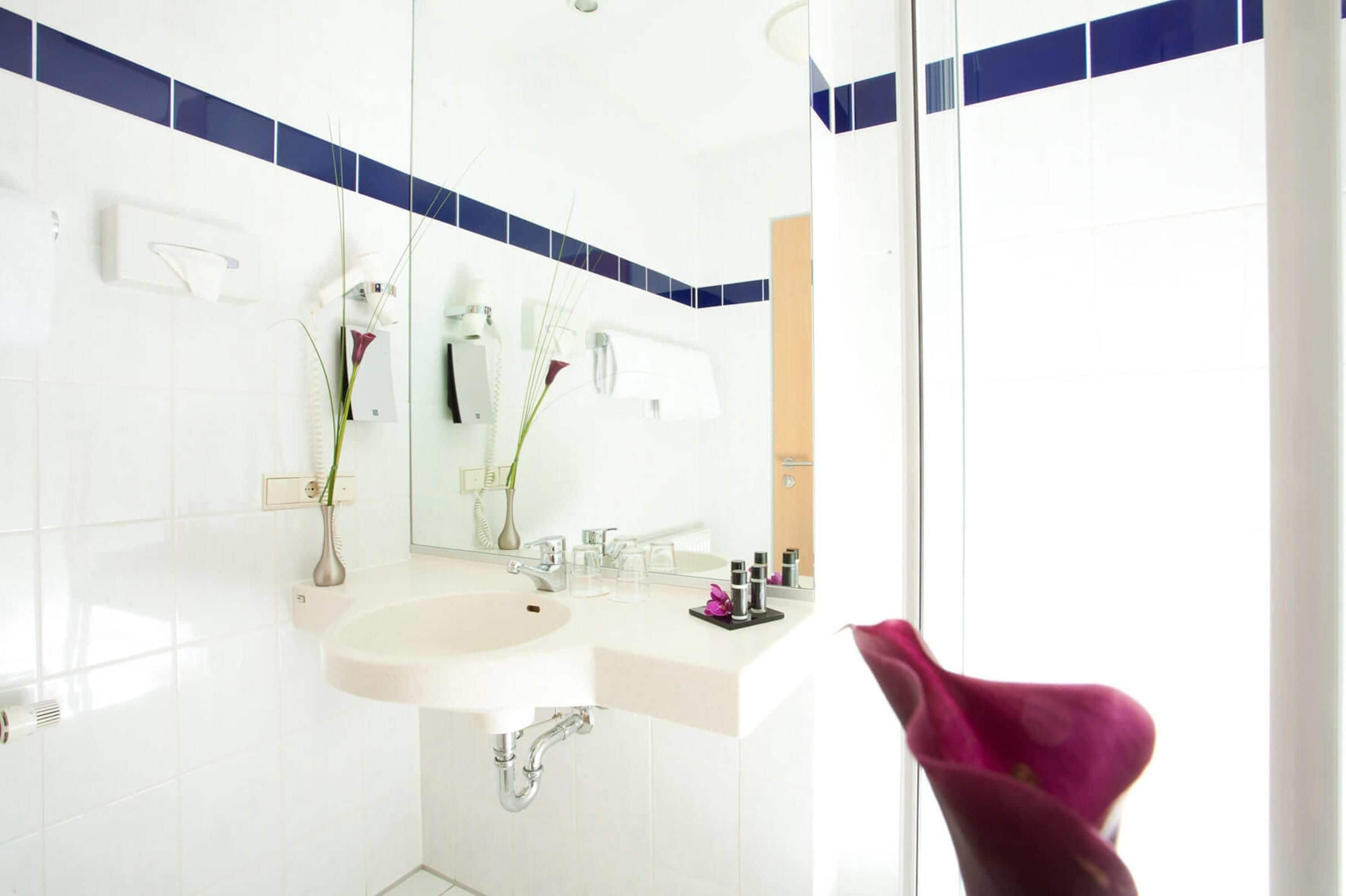 A modern bathroom with a white sink, a mirror, and a towel rack.