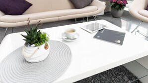 Una sala de estar moderna con un sofá blanco, una mesita de centro con una planta en maceta, una tableta y un teléfono inteligente.