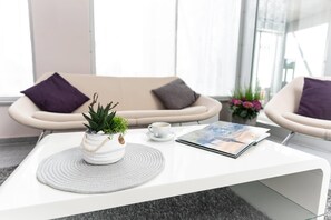 A modern, minimalist living area with a white coffee table, two armchairs, a sofa, and a potted plant. - elaya hotel wolfenbuettel, Trademark Collection by Wyndham (Wolfenbuettel)