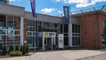 Un hôtel moderne avec une façade en verre, une façade extérieure en briques et un espace d’entrée pavé.