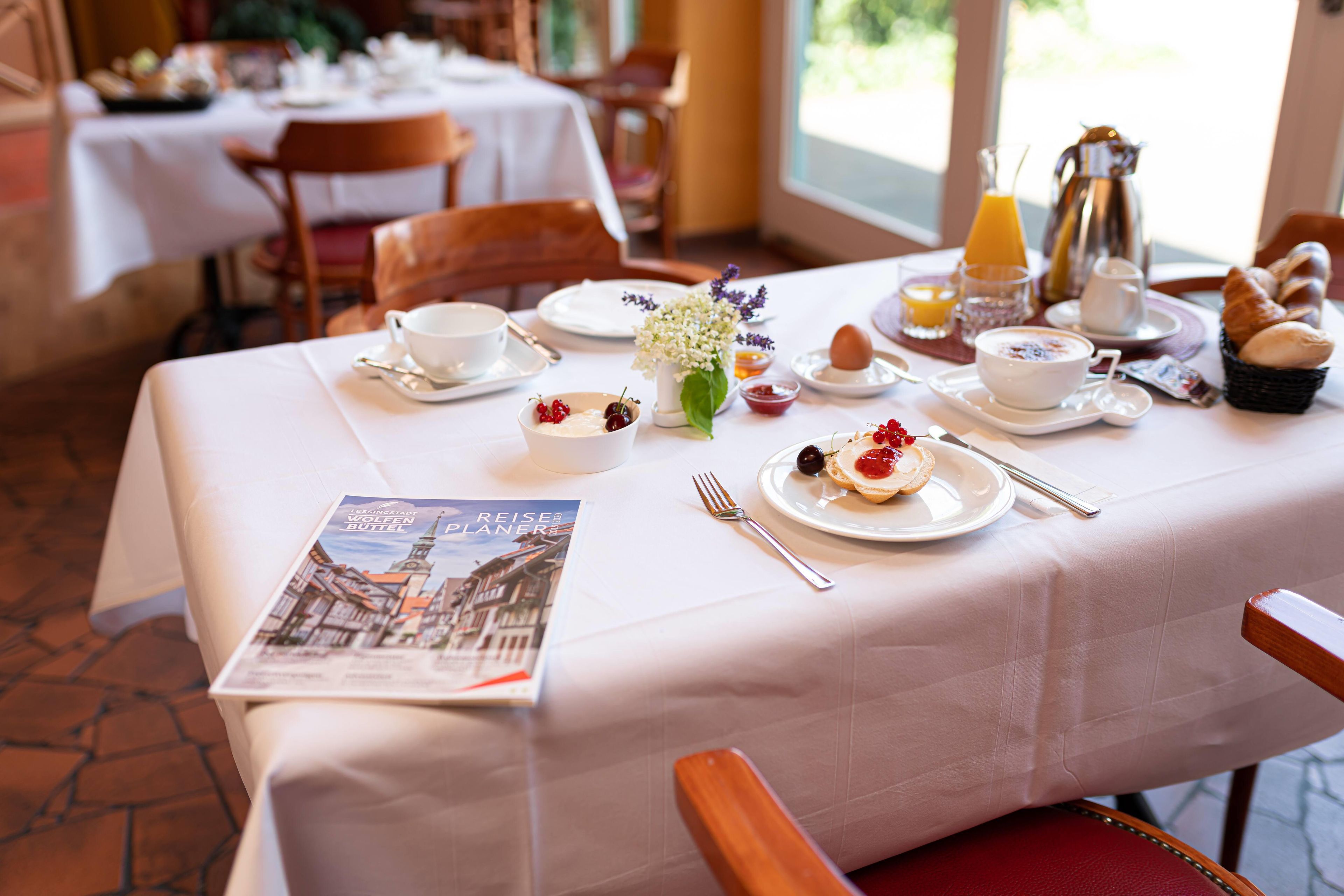A breakfast table set with plates, cups, and a menu.