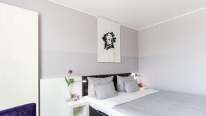 A modern hotel room with a large bed, a nightstand, a purple chair, and a wall-mounted artwork. - elaya hotel wolfenbuettel, Trademark Collection by Wyndham (Wolfenbuettel)