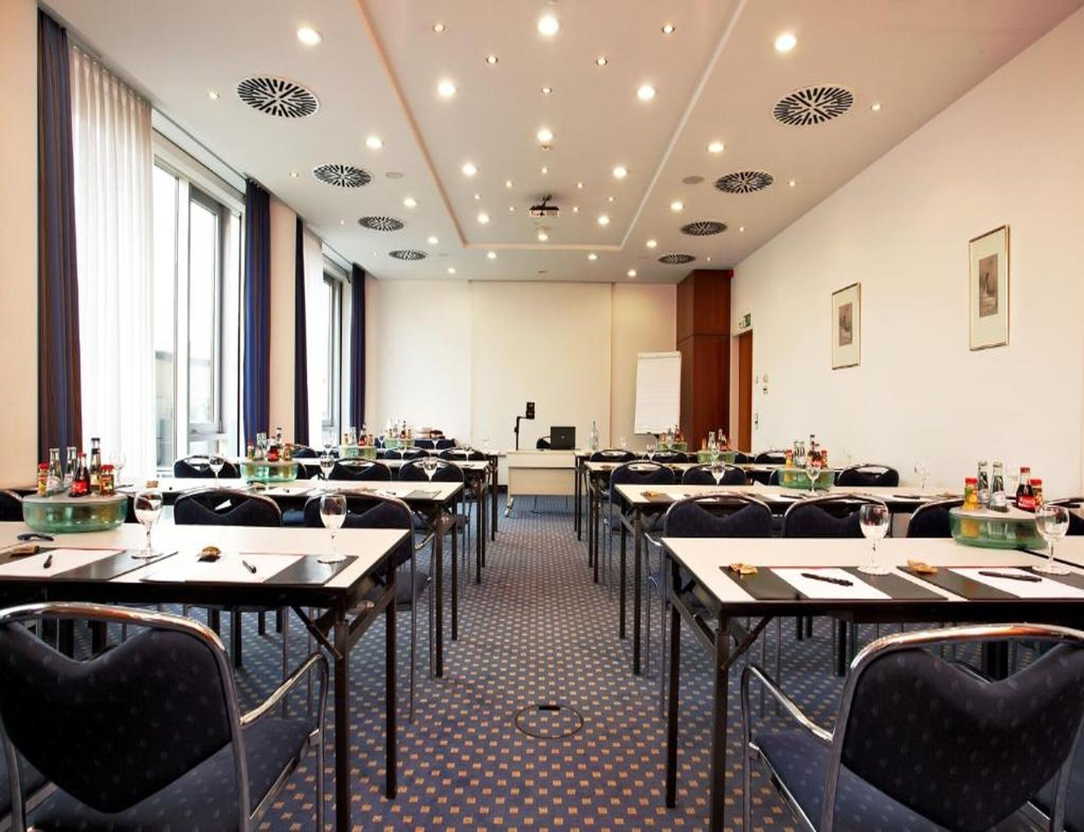 A conference room with tables, chairs, and a presentation screen.