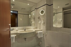 Un baño moderno con dos lavamanos, un espejo grande y un secador de pelo.