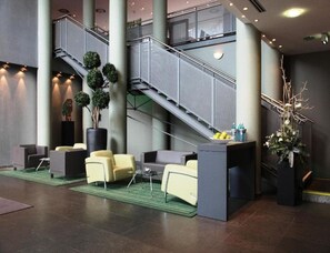 A lobby with a staircase, seating area, and decorative plants. - Sunday Hotel Kassel (Kassel)