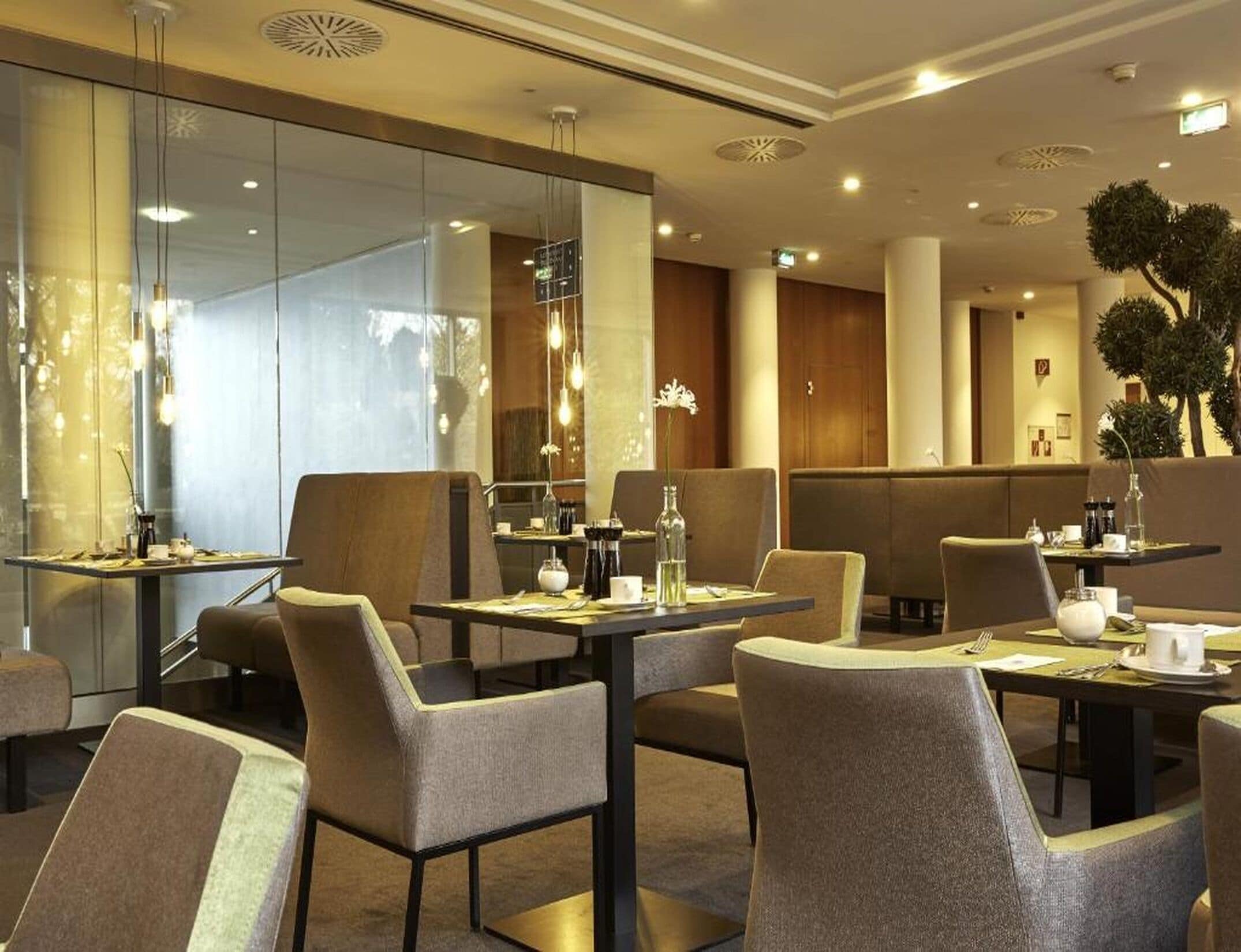 A modern hotel dining area with tables and chairs, ambient lighting, and a view of the interior.