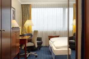 Ein Hotelzimmer mit Bett, Schreibtisch, Stuhl und zwei Lampen.