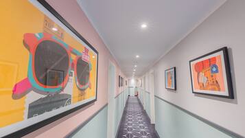 A hallway with framed artwork on the walls, a patterned carpet, and a ceiling with recessed lighting.