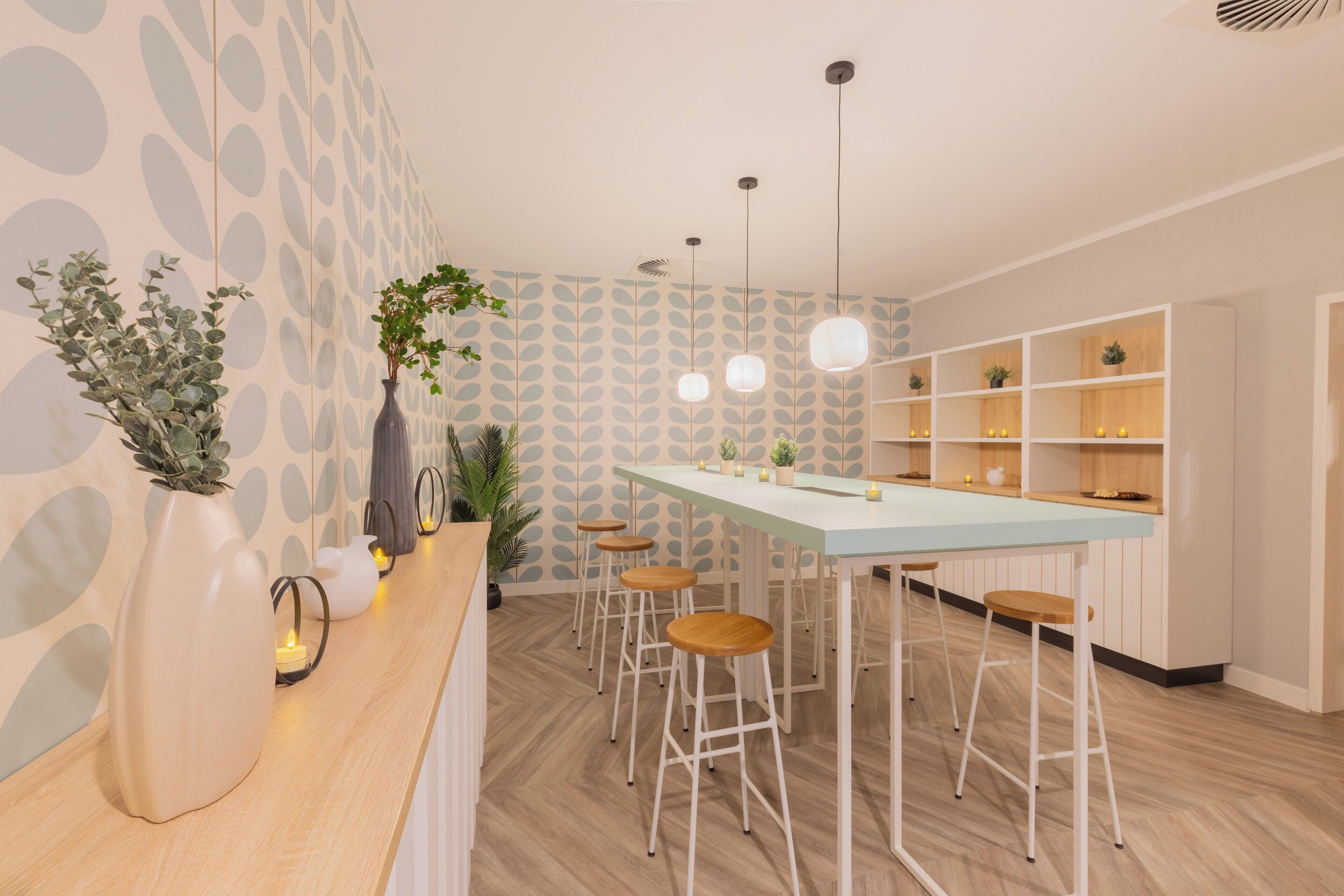 Una cocina moderna con encimera azul claro, taburetes de bar blancos y un papel tapiz estampado.