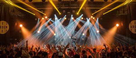 A concert with a crowd facing a stage under bright stage lights.