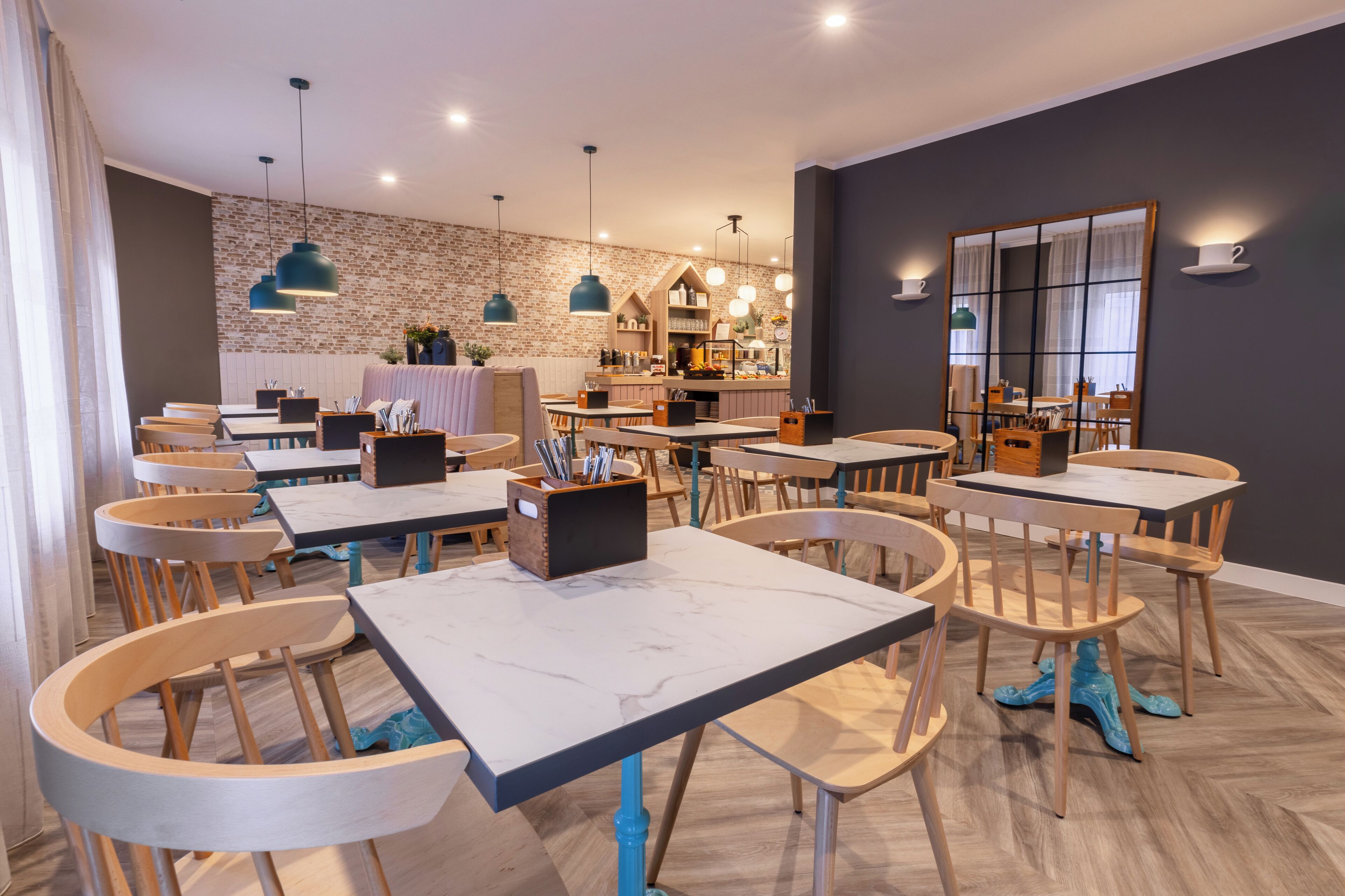 Un restaurante moderno con sillas y mesas de madera, pared de ladrillo e iluminación colgante.