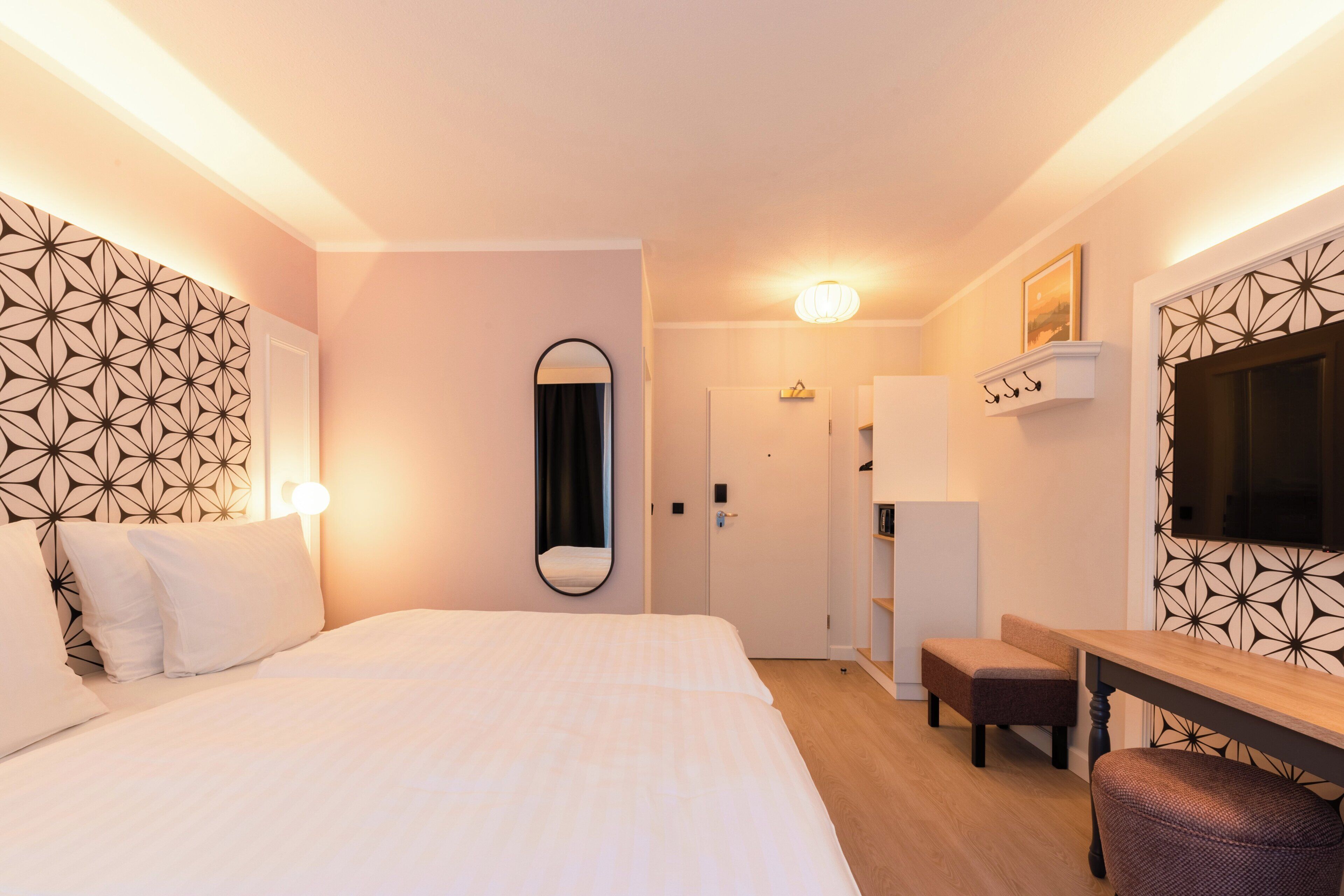 Una habitación de hotel con una cama grande, un escritorio, un espejo y un televisor.