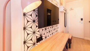 A modern room with a wooden dining table, a mounted TV, and a patterned wall. - Garner Hotel Mannheim City by IHG (Mannheim)
