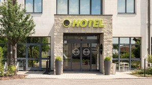Entrada de hotel con fachada moderna, ventanas amplias y un llamativo letrero que dice 'HOTEL'.