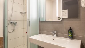 Un baño con ducha, lavabo y espejo.