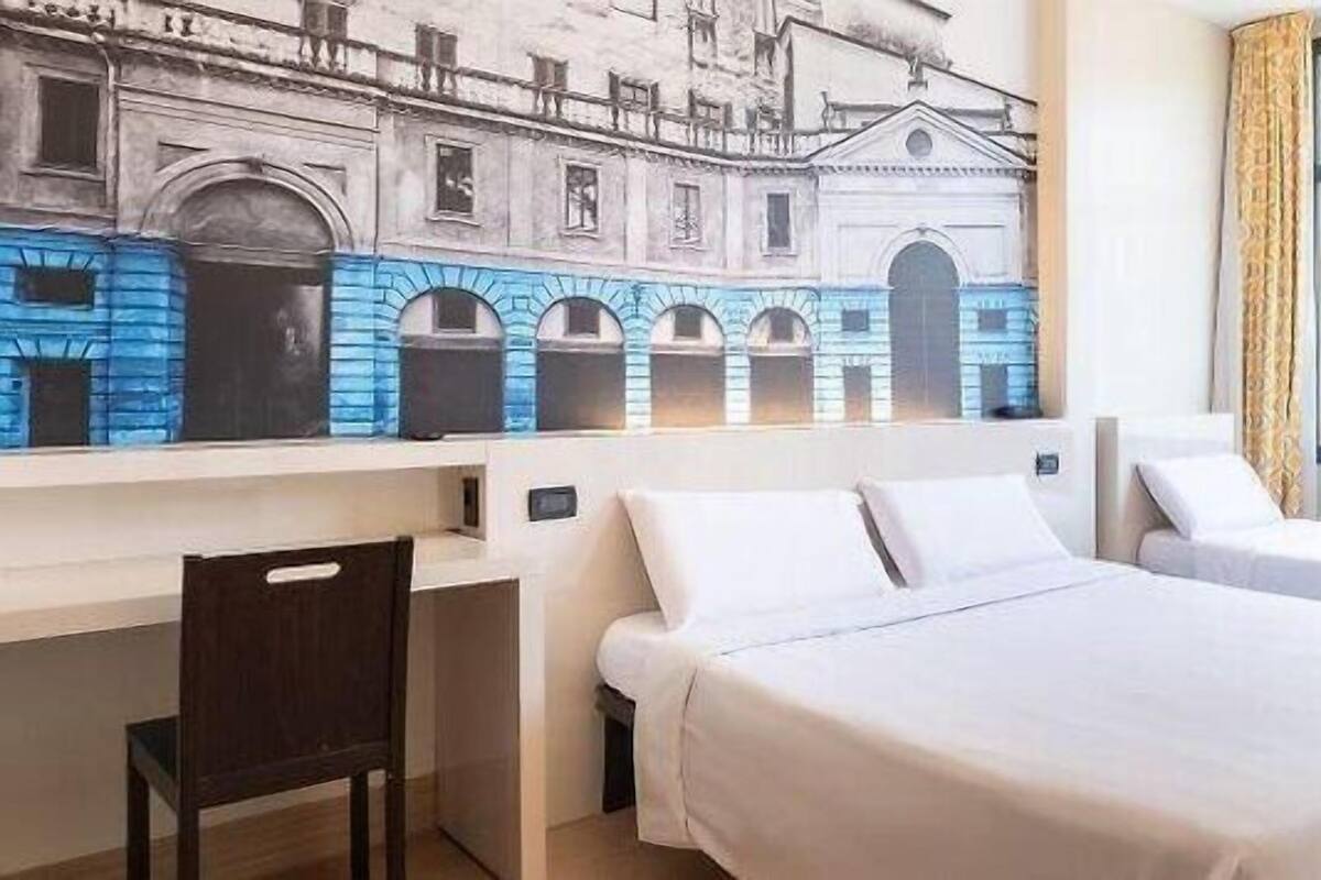 A hotel room with two beds, a desk, and a chair.
