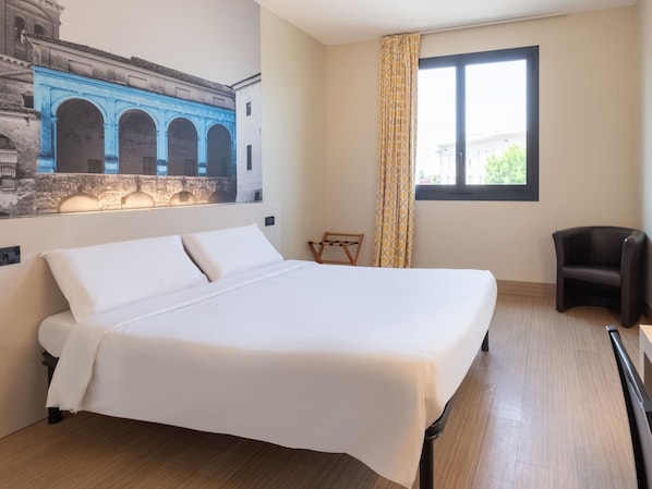 A hotel room with a large bed, a chair, a window with curtains, and a mural of a historical building on the wall. - B&B Hotel Mantova (San Giorgio di Mantova)