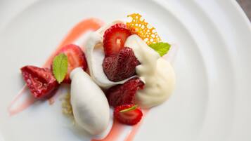 Un plato de postre con fresas, menta y una rodaja de naranja decorativa.