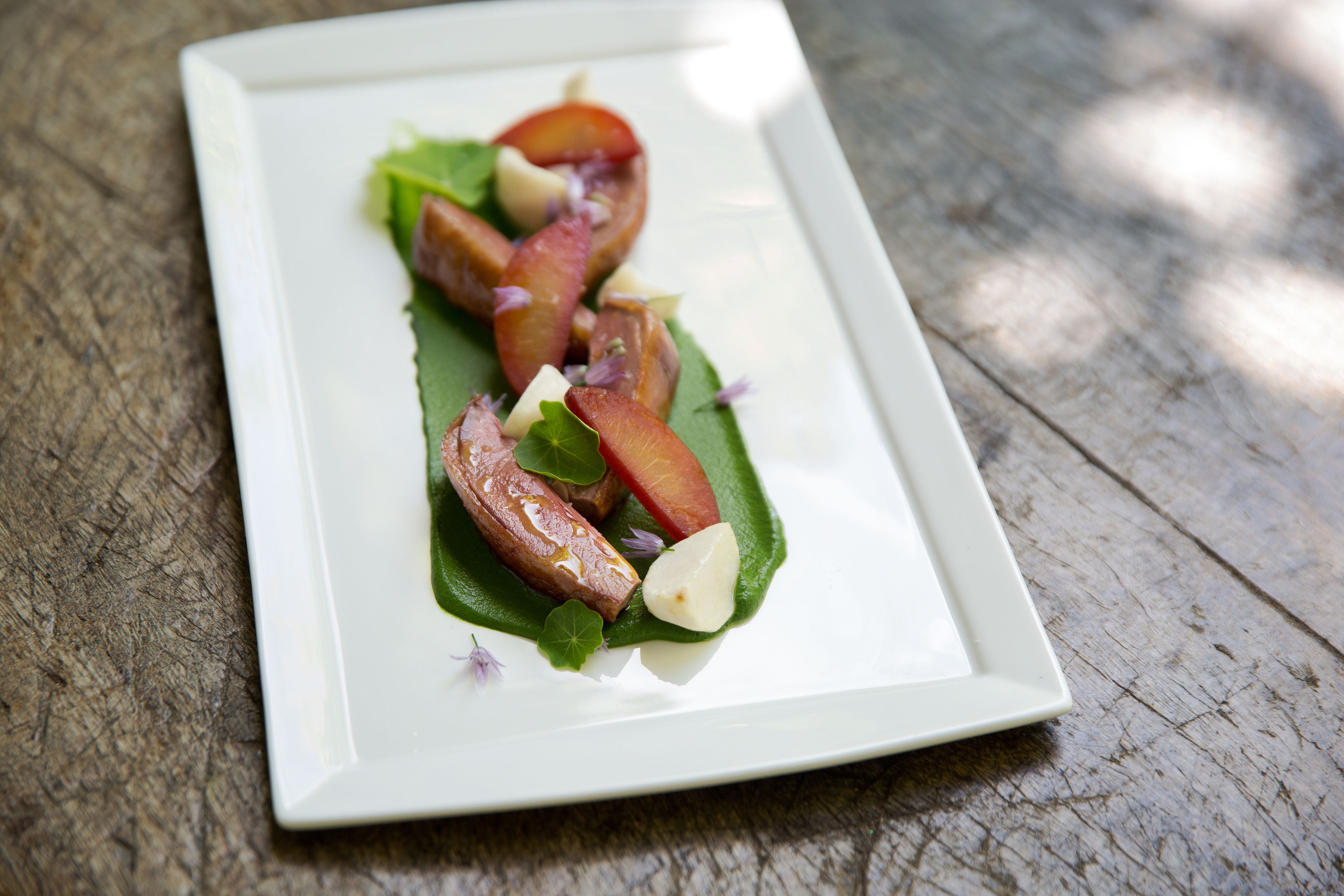 A rectangular white plate with a food arrangement on a wooden surface.
