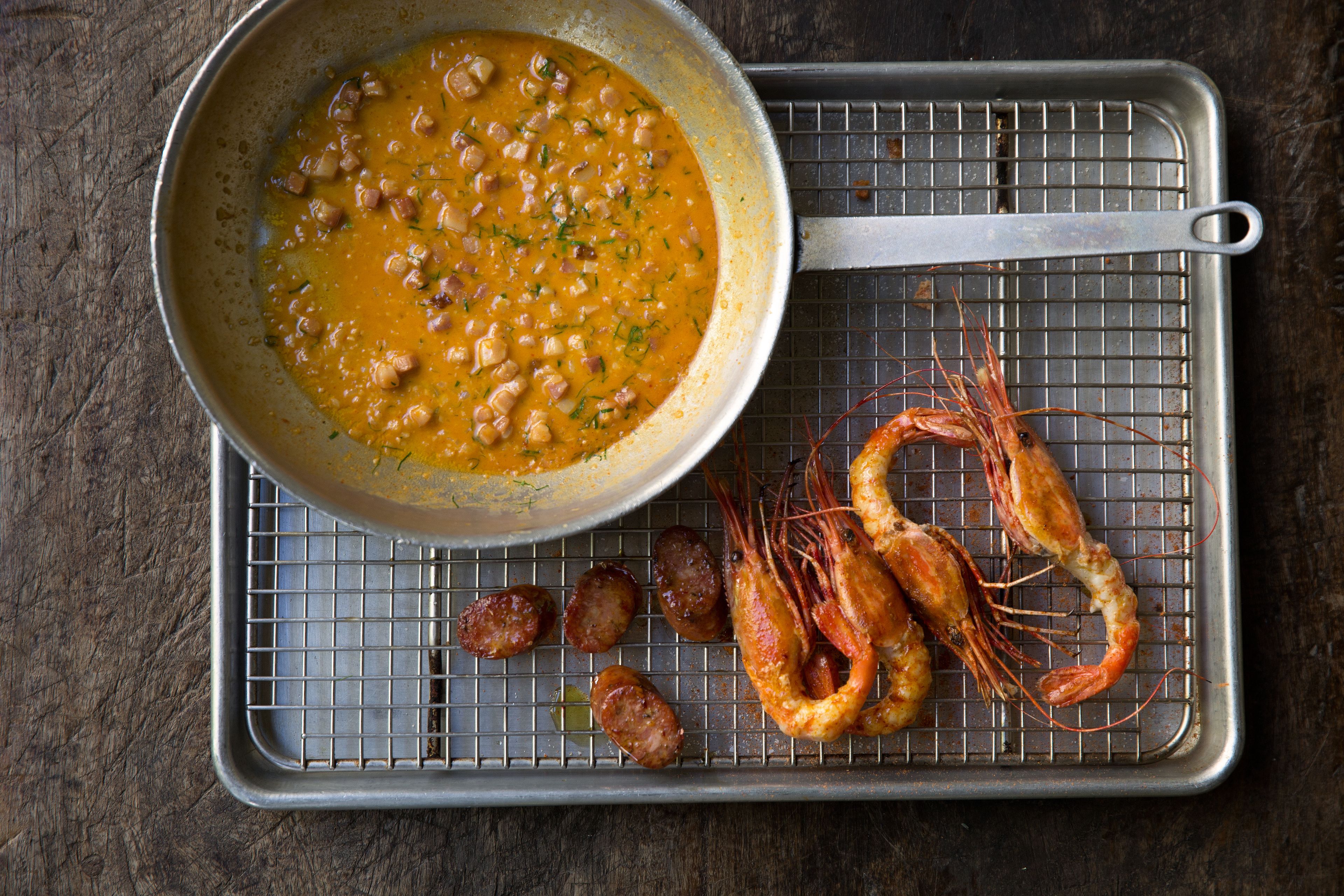 A pan of soup with shrimp and sausage on a cooling rack.