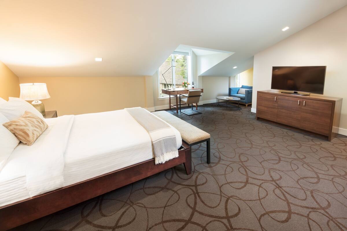 A hotel room with a large bed, a desk, a television, and a view of the outdoors.