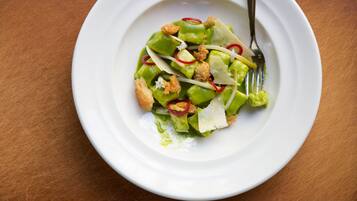 Un plato blanco con una ensalada verde sobre una mesa de madera.