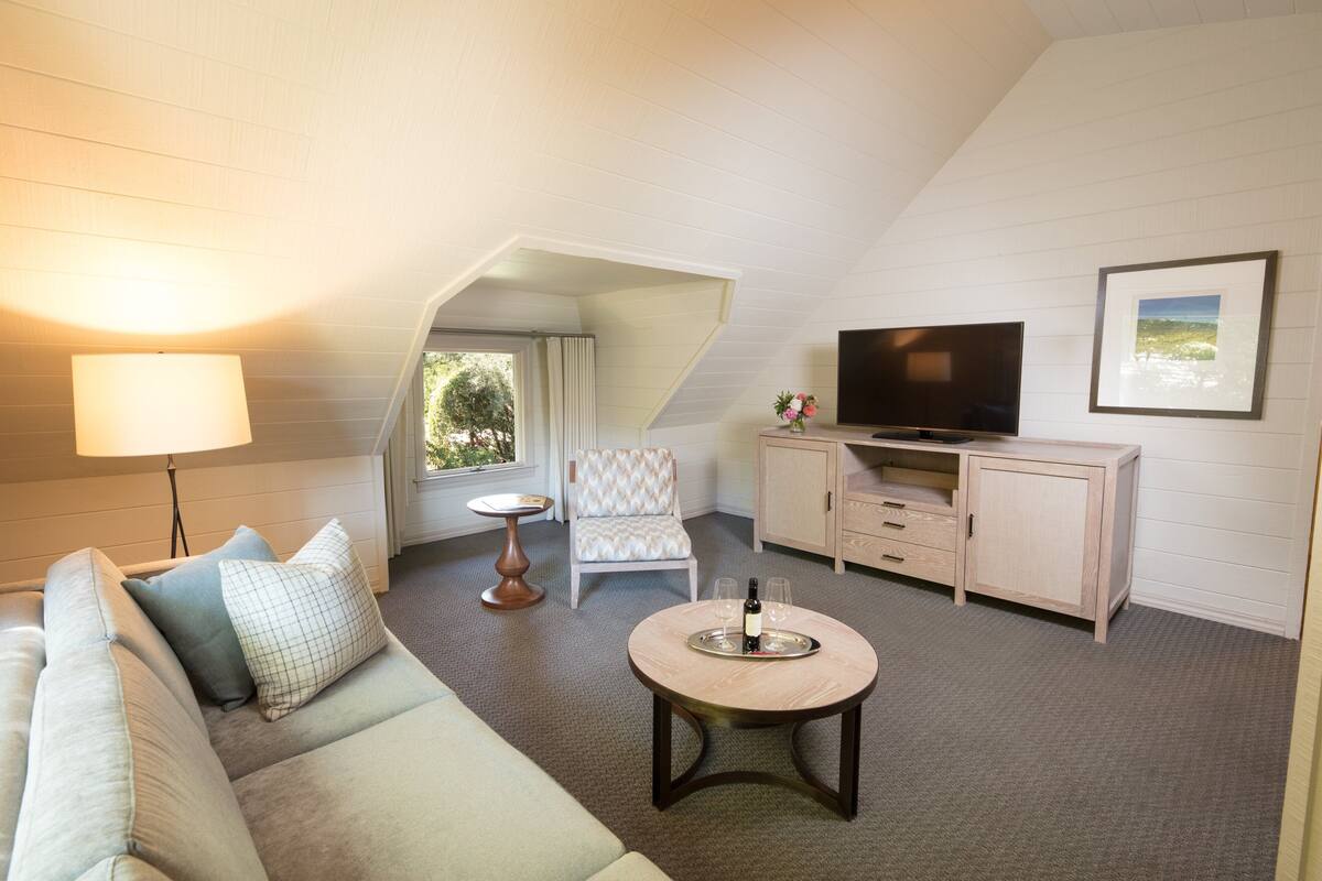 A cozy room with a sofa, a small table with a tray, a television, and a cabinet.