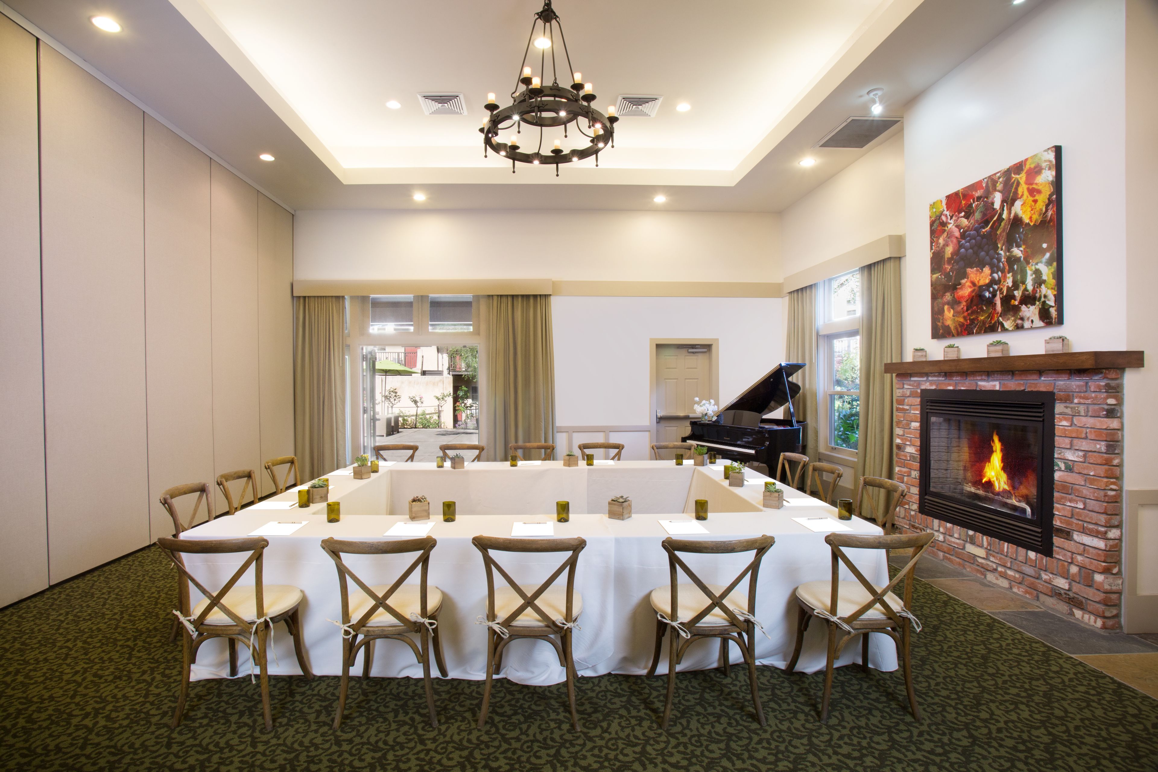 A conference room with a long table, chairs, a fireplace, and a piano.
